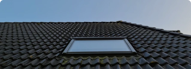 Construcción de Tejados y Cubiertas 10 Tejados Alcala Henares Tejado con tejas oscuras y ventana instalada como parte de un proyecto de construcción de tejados y cubiertas en una vivienda residencial