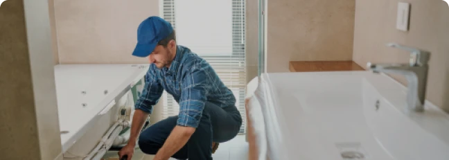 Reformas integrales 13 Tejados Alcala Henares Técnico realizando reformas integrales en un baño, ajustando instalaciones para mejorar la funcionalidad y modernizar el espacio con nuevos equipos