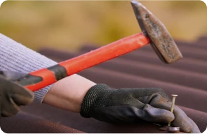 Instalación de Onduline Bajo Teja 2 Tejados Alcala Henares Trabajador asegurando la instalación de onduline bajo teja con martillo y clavos, garantizando la estabilidad y protección del tejado