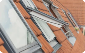 Instalación de ventanas Velux en tejados inclinados con tejas rojas, optimizando la ventilación y la luz natural en viviendas ubicadas en Alcalá de Henares